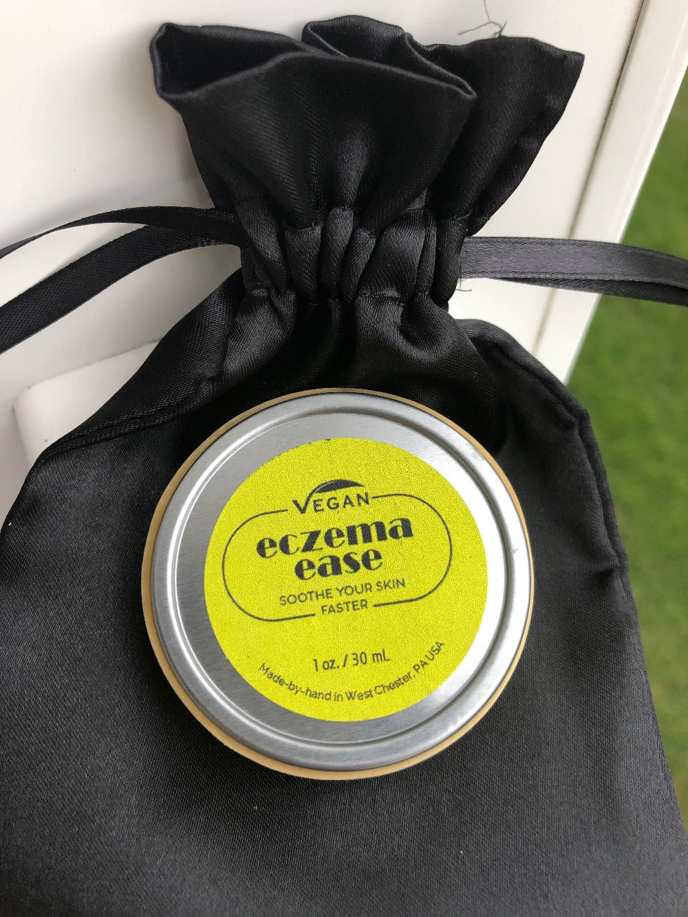 eczema ease balm in round flat tin with a black satin gift bag by nicmarie